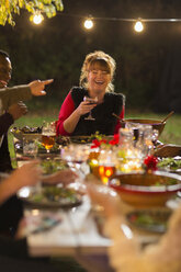 Glückliche Frau lacht, genießt Abendessen Gartenparty mit Freunden - CAIF23262