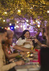 Freunde stoßen mit Weingläsern an und genießen das Abendessen auf einer Gartenparty - CAIF23267