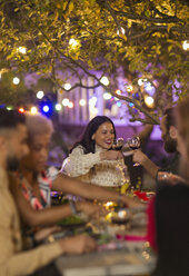 Friends toasting wine glasses, enjoying dinner garden party - CAIF23267