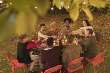 Freunde stoßen mit Wein an und genießen das Abendessen auf einer Gartenparty - CAIF23270