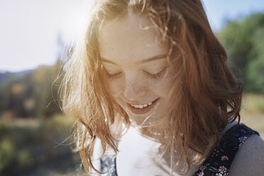 Smiling young woman with freckles looking down - CAIF23277