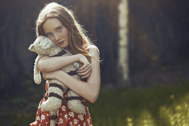 Portrait serene tween girl with stuffed animal in park - CAIF23318