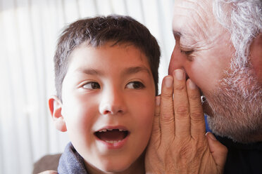 Hispanic grandfather whispering secret to grandson - BLEF00191