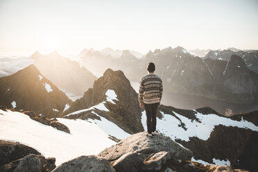 Kaukasischer Mann steht auf einem Felsen und bewundert die malerische Aussicht auf einen Bergsee - BLEF00199