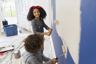 Porträt glückliches Mädchen malt Wand mit Bruder - CAIF23351