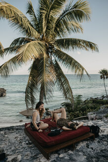 Mexiko, Quintana Roo, Tulum, zwei glückliche junge Frauen entspannen sich am Strand - LHPF00662