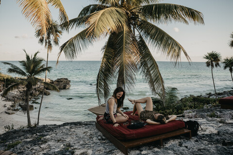 Mexiko, Quintana Roo, Tulum, zwei glückliche junge Frauen entspannen sich am Strand, lizenzfreies Stockfoto