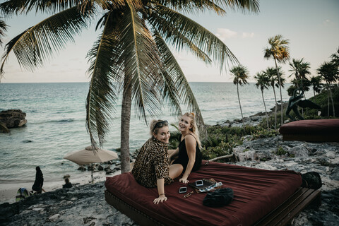 Mexiko, Quintana Roo, Tulum, zwei glückliche junge Frauen entspannen sich am Strand, lizenzfreies Stockfoto