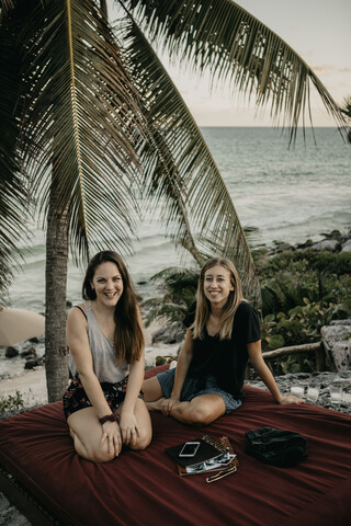 Mexiko, Quintana Roo, Tulum, zwei glückliche junge Frauen entspannen sich am Strand, lizenzfreies Stockfoto