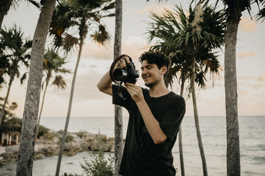 Mexico, Quintana Roo, Tulum, young man taking pictures on the beach - LHPF00669