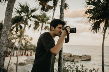 Mexico, Quintana Roo, Tulum, young man taking pictures on the beach - LHPF00670