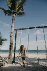 Mexiko, Quintana Roo, Tulum, junge Frau auf einer Schaukel am Strand - LHPF00679