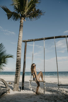 Mexiko, Quintana Roo, Tulum, glückliche junge Frau auf einer Schaukel am Strand - LHPF00680