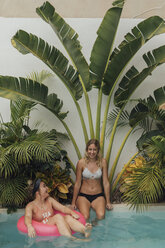 Zwei glückliche junge Frauen entspannen sich im Schwimmbad - LHPF00684