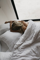 Blond young woman lying in bed - LHPF00699