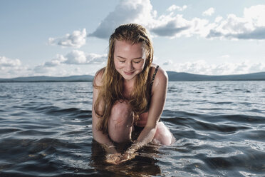 Caucasian teenage girl kneeling in ocean - BLEF00277