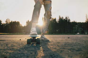 Legs of Caucasian teenage girl standing on skateboard - BLEF00280