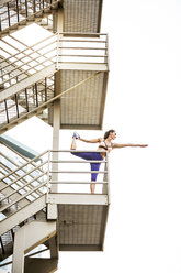 Caucasian woman stretching leg on urban staircase - BLEF00286