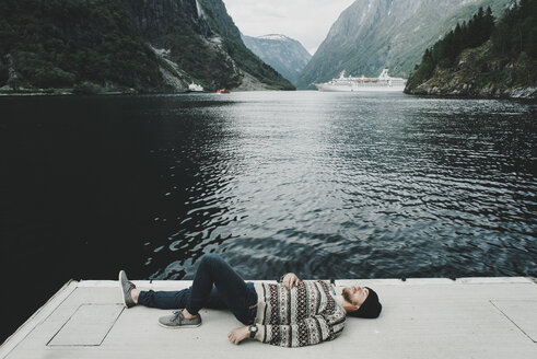 Caucasian man laying on dock at waterfront - BLEF00295