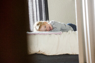 Kaukasisches Mädchen liegt auf dem Bett jenseits der Türöffnung - BLEF00308