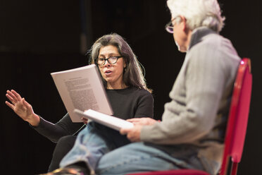 Hispanic man and woman reading scripts on theater stage - BLEF00317