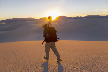 Caucasian man carrying camera and tripod in desert - BLEF00336