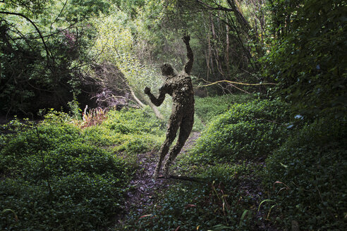 Man covered with rocks with arms raised in forest - BLEF00341