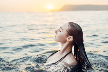 Kaukasische Frau beim Schwimmen im Sonnenuntergang - BLEF00393