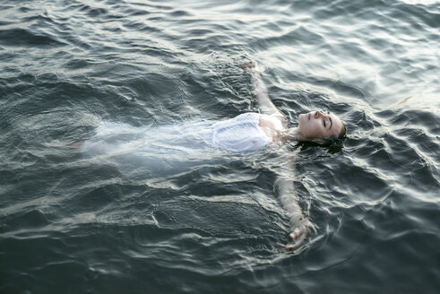 Caucasian woman wearing a dress floating in water - BLEF00395