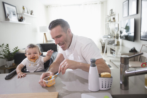 Vater füttert glückliches Baby Sohn, lizenzfreies Stockfoto