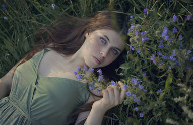 Caucasian woman laying in grass with wildflowers - BLEF00483