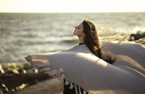 Wind weht Schal der kaukasischen Frau am Strand, lizenzfreies Stockfoto