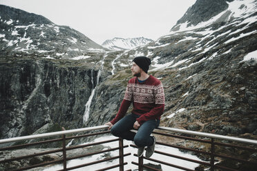 Caucasian man sitting on balcony railing admiring snow on mountain - BLEF00554