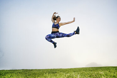 Gemischtrassige Frau beim Training und Springen im Feld - BLEF00630