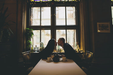 Kaukasisches Paar sitzt am Tisch und reibt sich die Nasen - BLEF00650
