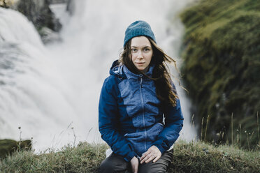 Porträt einer ernsten kaukasischen Frau, die in der Nähe eines Wasserfalls sitzt - BLEF00687