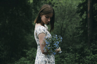 Kaukasische Frau hält Blumen im Wald - BLEF00744