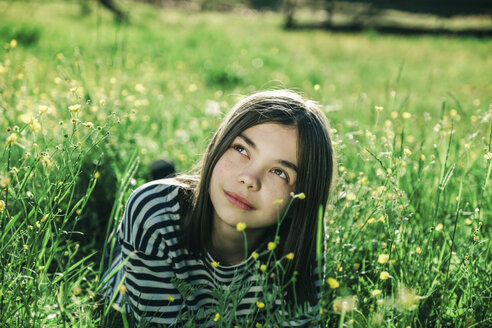 Lächelndes kaukasisches Teenager-Mädchen, das im Gras liegt - BLEF00753