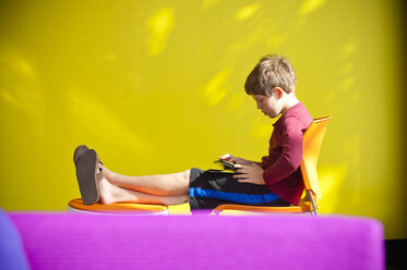 Kaukasischer Junge, der sich entspannt und ein digitales Tablet liest - BLEF00778
