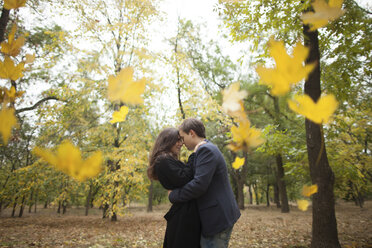 Autumn leaves falling near hugging Caucasian couple - BLEF00798