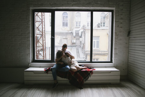 Caucasian couple kissing on bench near window - BLEF00800