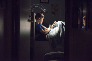 Kaukasischer Junge liest nachts im Bett ein Buch - BLEF00847