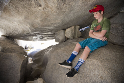 Nachdenklicher kaukasischer Junge sitzt auf Felsen - BLEF00849