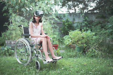 Mixed race girl in wheelchair using virtual reality goggles in backyard - BLEF00906