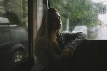 Pensive Caucasian woman sitting on bus in rain - BLEF00944