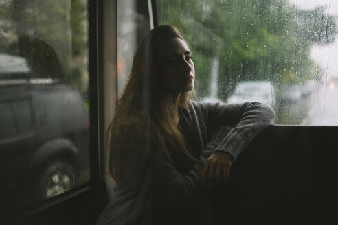 Nachdenkliche kaukasische Frau sitzt im Bus im Regen - BLEF00944