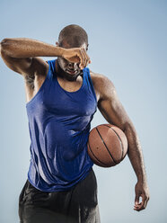 Black man holding basketball wiping sweat off forehead - BLEF01007