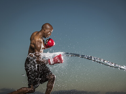 Water splashing on black boxer punching stock photo