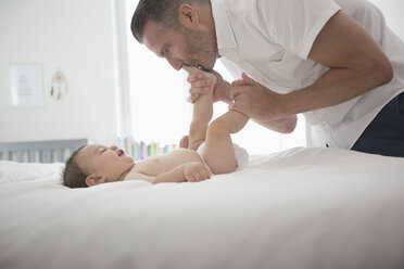 Vater küsst die Füße seines kleinen Sohnes im Bett - BLEF01037