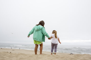 Caucasian mother and daughter holding hands on beach - BLEF01045